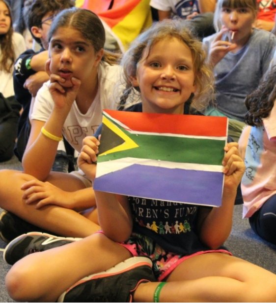 Young girl smiling and holding a South African flag at a youth program